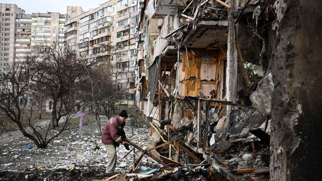 A man clears debris in the Ukrainian capital Kyiv, where a military shell hit several buildings at the start of the war. Picture taken on 25 February 2022.