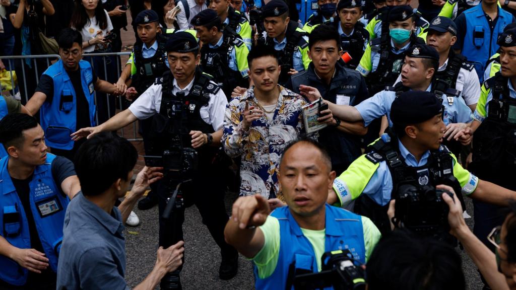 Lee Yue-shun is escorted by police outside the West Kowloon Magistrates' Courts building