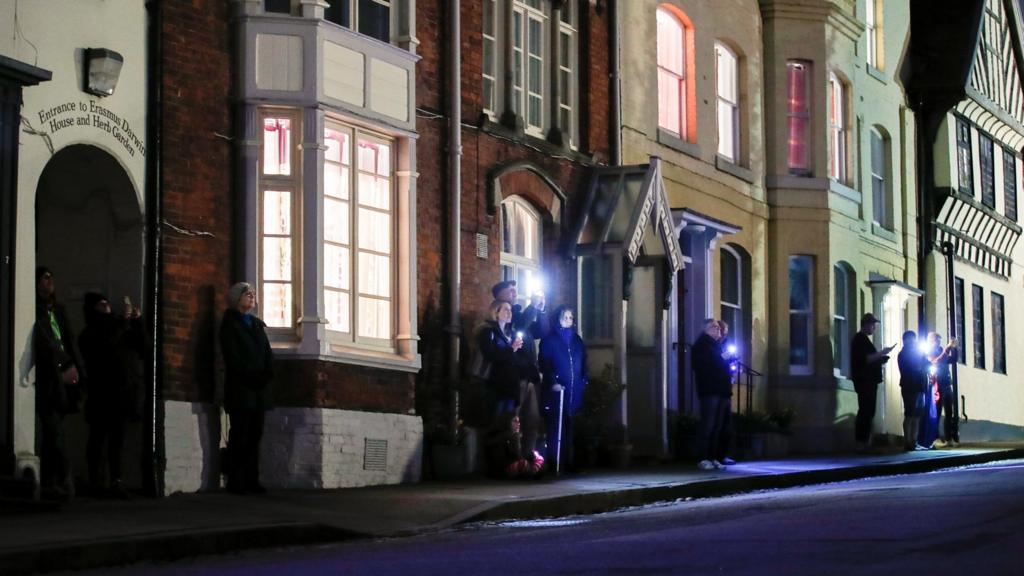 People light up their cell phones while they stand outside, as part of a day of reflection to mark the anniversary of Britain's first coronavirus disease (COVID-19) lockdown, in Lichfield, Britain March 23, 2021.