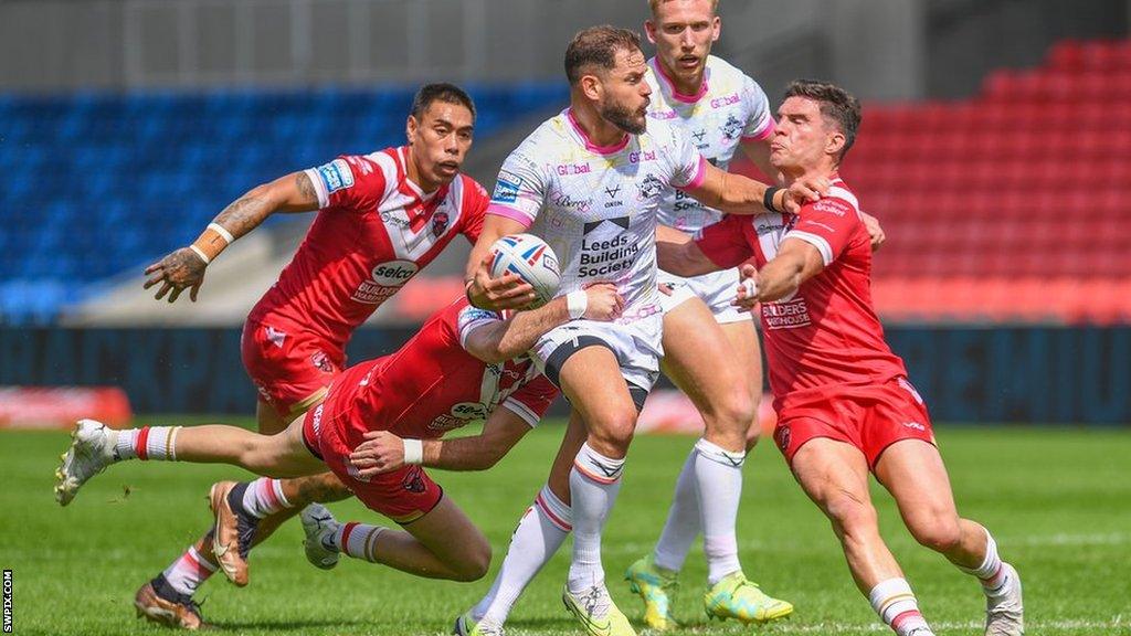 Aidan Sezer of Leeds Rhinos is tackled by Brodie Croft of Salford Red Devils