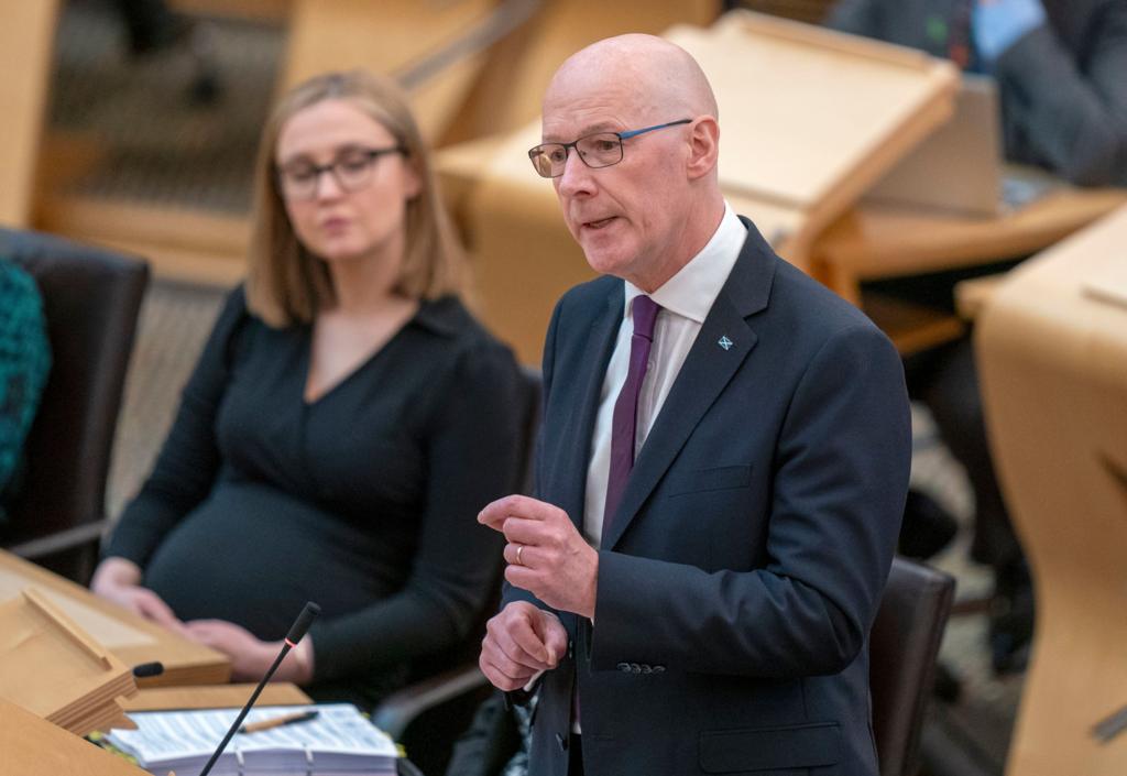 First Minister John Swinney speaks in the Scottish Parliament's chamber