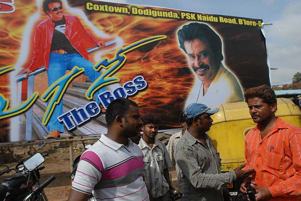 Fans near a billboard of Indian film superstar Rajinikanth in southern India.