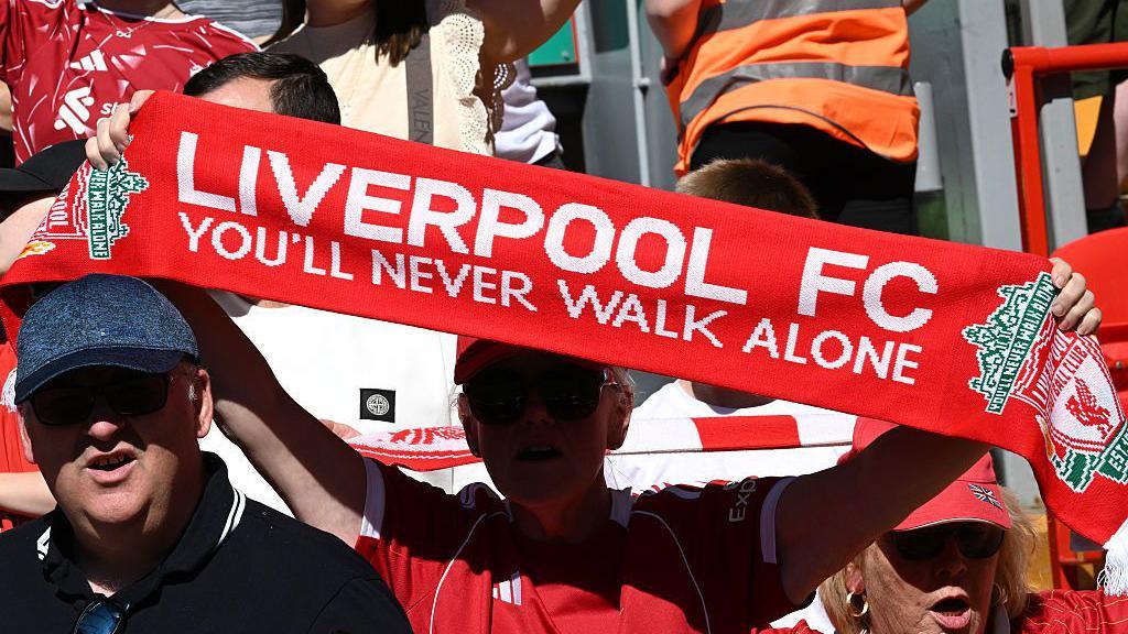 Liverpool fan holds up You'll Never Walk Alone scarf