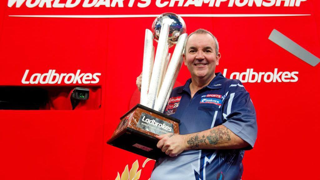 Phil Taylor holding the World Matchplay trophy in 2013