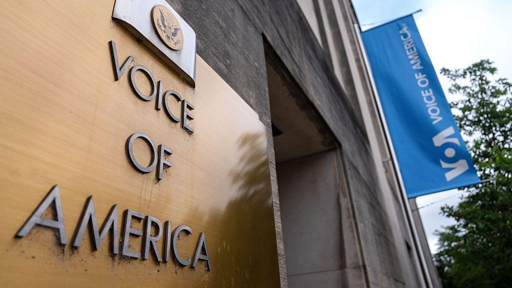 A gold plaque on a building says Voice of America