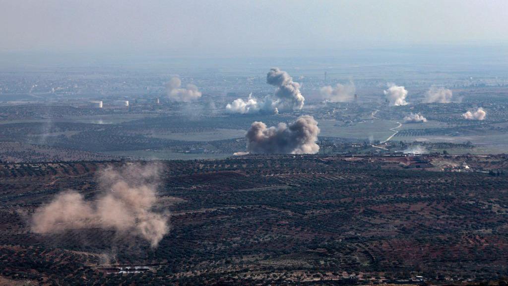 Smoke rises from multiple locations on the outskirts of Saraqeb in north-west Syria during a rebel offensive against government forces, as seen from Ariha (28 November 2024)