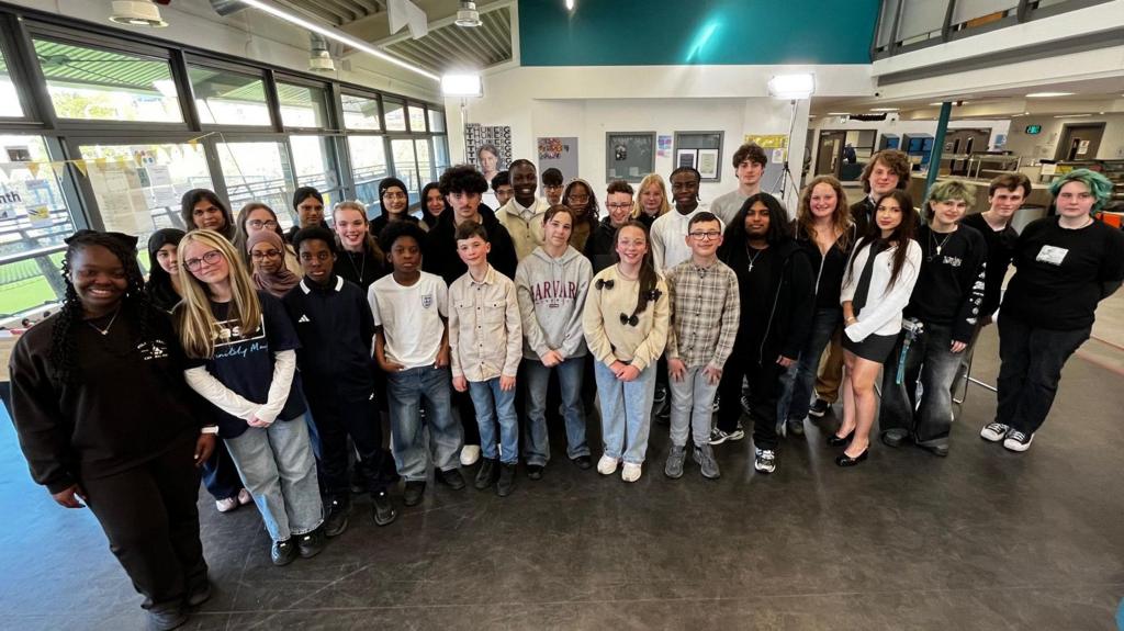 A young of young people posing for a photo in a television studio.