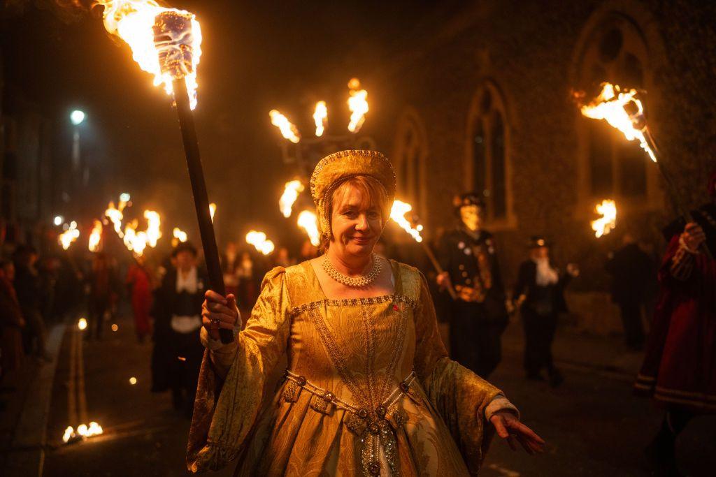 A woman carries a burning torch through the street of Lewes