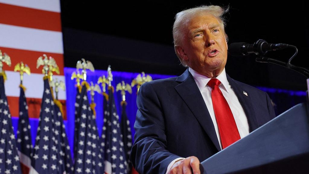 Donald Trump speaks while standing at his lecturn onstage with a US flag in the background