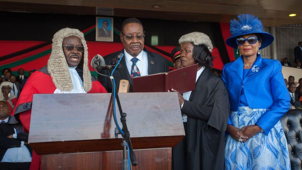 Malawi's President elect Arthur Peter Mutharika is sworn in for his second term by Chief Justice Andrew Nyirenda (L) and Registrar of the high Court and Supreme Court Of appeal (2R) as First Lady Gertrude Mutharika looks onat Kamuzu Stadium in Blantyre on May 28, 2019, after a contentious election marred by allegations of fraud and vote-rigging. - The Malawi Electoral Commission announced on Monday that Mutharika, who heads the ruling Democratic Progressive Party (DPP), had narrowly won last week's vote after an injunction barring the release of the results was lifted.