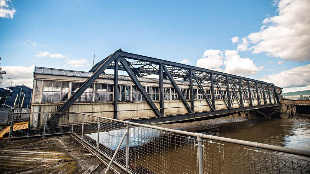 A bridge on Tilbury Port. It looks like a greenhouse and has artwork to honour the Windrush generation