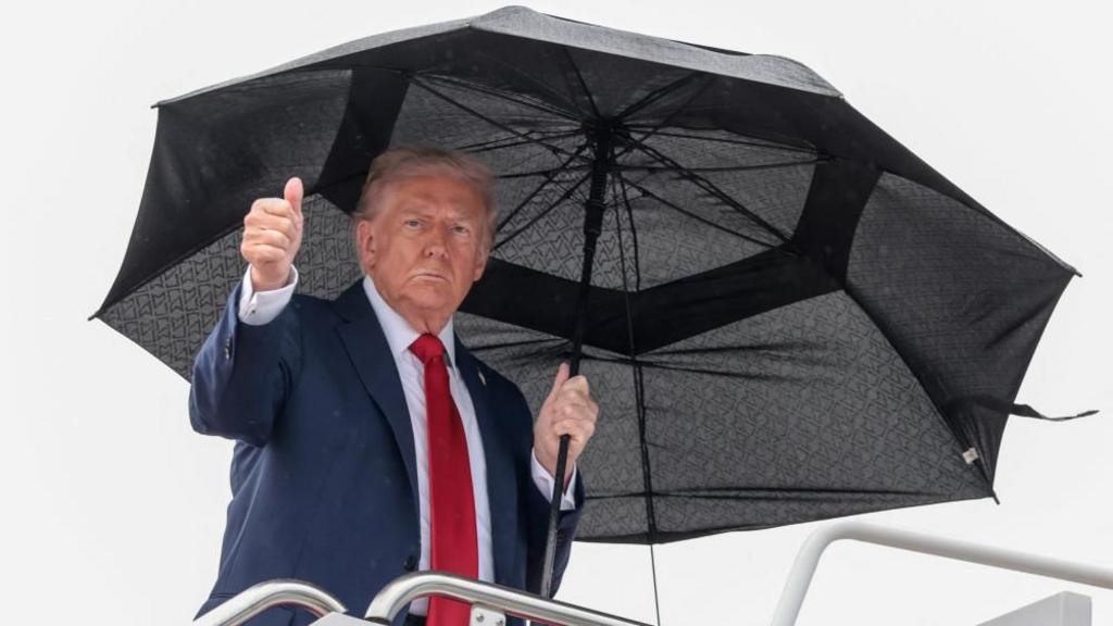 Trump holding umbrella boarding plane.