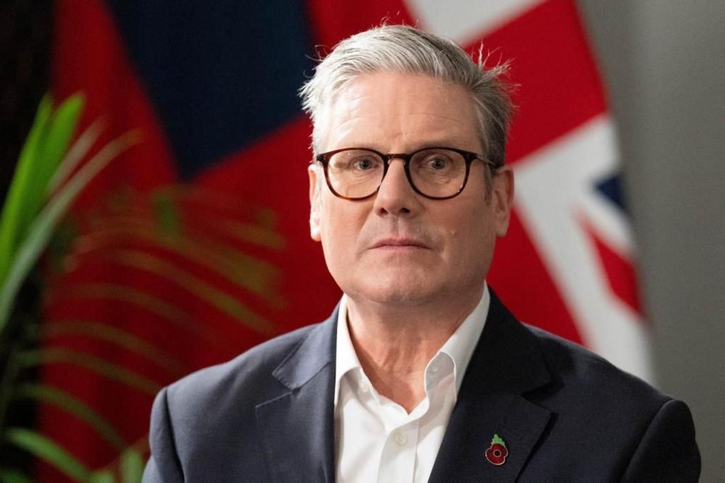 British Prime Minister Keir Starmer sitting in front of a British flag and a plant