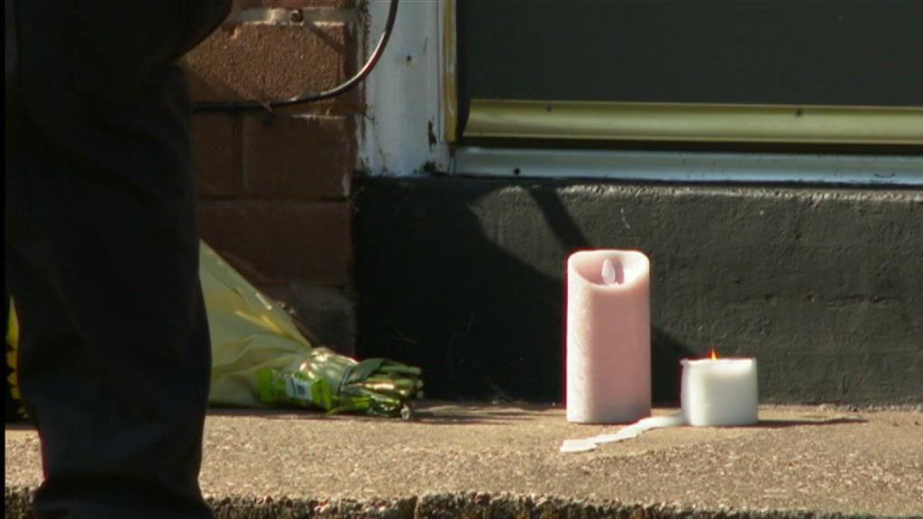 Two candles, one pink and white, sitting outside a house