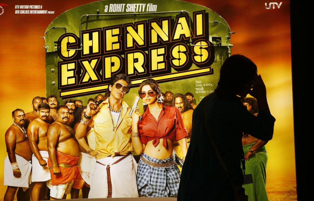 A man walks past a poster for the Indian film Chennai Express, starring Shah Rukh Khan and Deepika Padukone