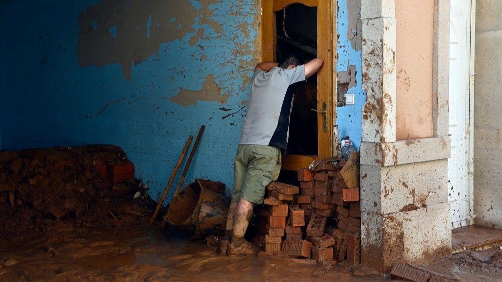  A man leans on a broken door 