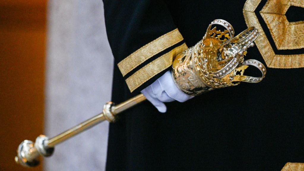 An ornate golden staff is carried by a uniformed officer wearing white gloves (image is from the London mayoral Silent Ceremony on 8 November 2024)