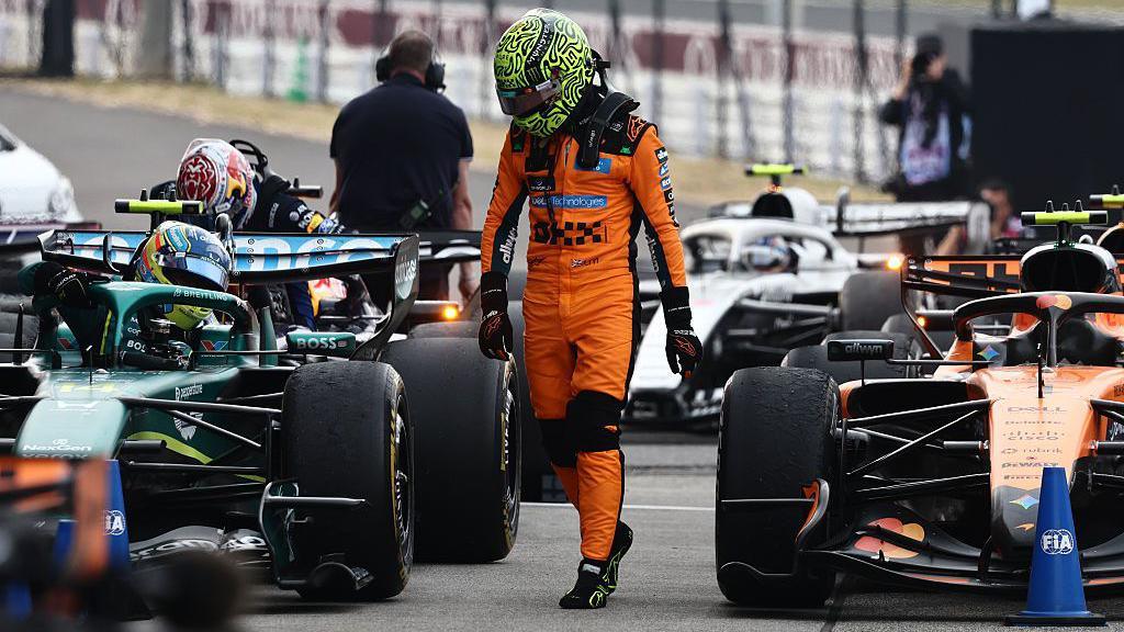 Lando Norris walks past a line of cars after the Japanese Grand Prix 