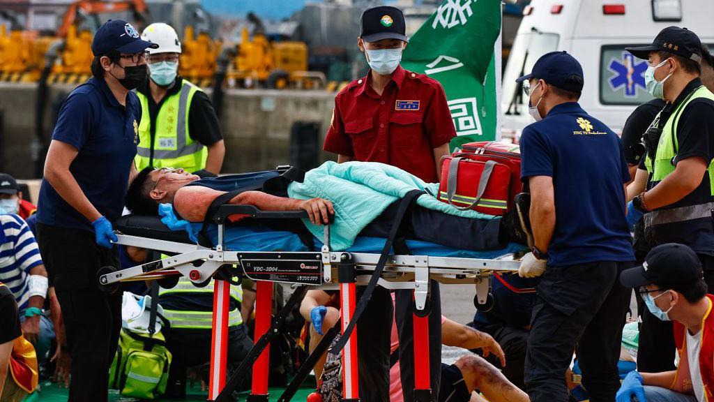 A man covered in fake blood is moved on a stretcher to an ambulance by emergency workers clad in blue uniforms and wearing face masks, during a war and disaster drill in Taiwan