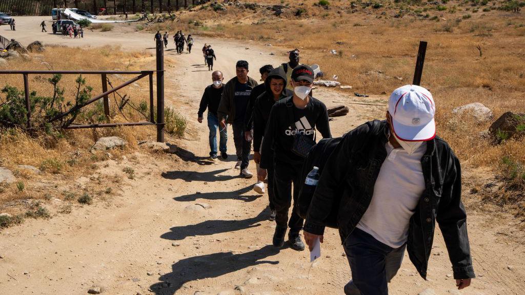 Migrants walk on a road waiting to be processed by the U.S. Border Patrol near the Jacumba Hot Springs after crossing the US-Mexico border on June 13, 2024 in San Diego, California. 