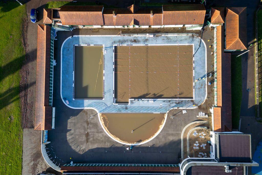  An aerial view of Pontypridd Lido showing the red tile of the changing rooms and the blue tiling poolside. But the water is brown. 