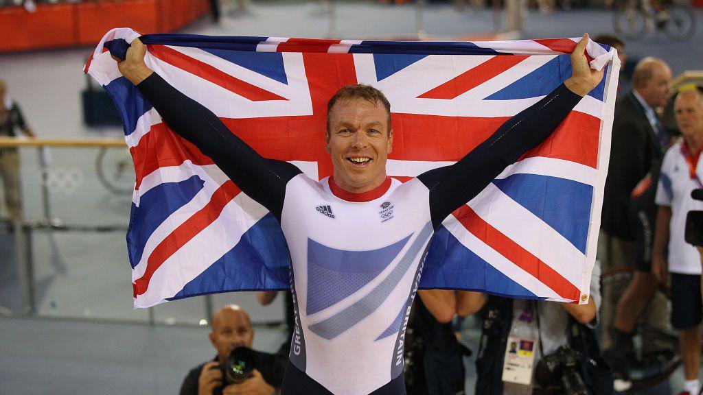 Chris Hoy in his cycling outfit holds behind him the Union flag following a win at the London 2012 Olympics