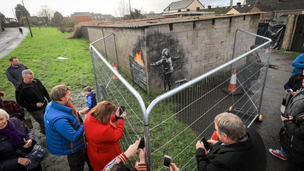 Criw yn edrych ar furlun Banksy