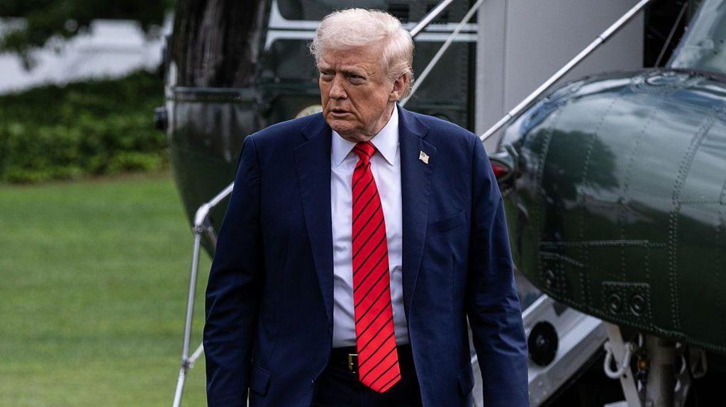 Donald Trump walks away from a helicopter wearing a suit and red tie after he returns to the White House following a visit to Walter Reed National Military Medical Center on 10 October 2025.