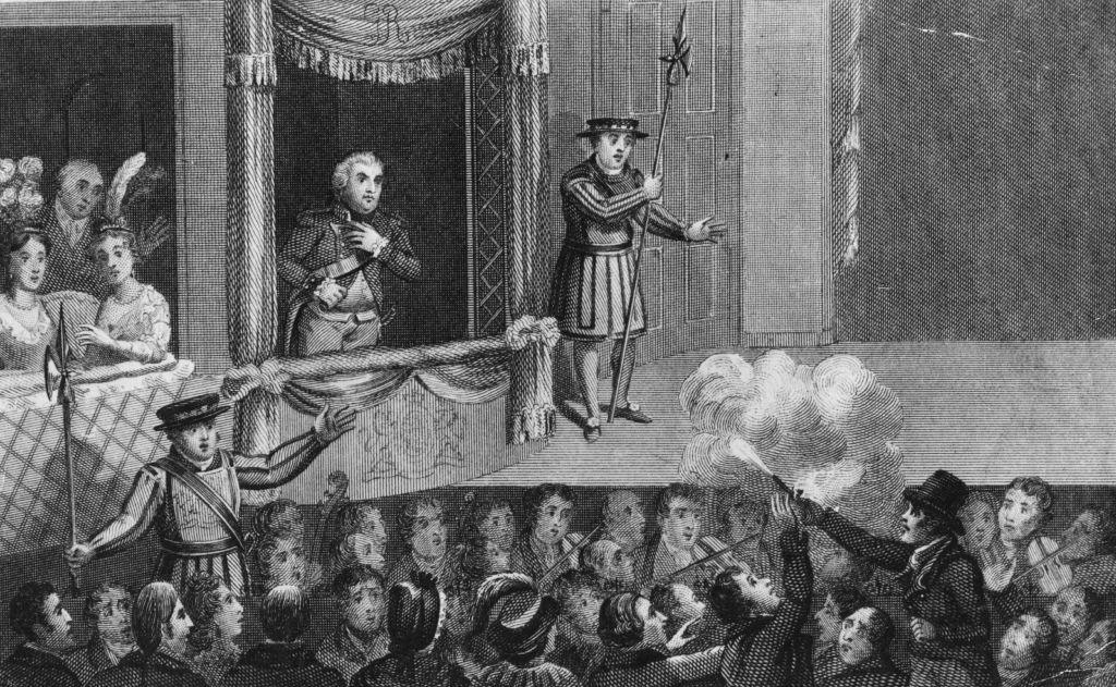 A black and white drawing of a crowded theatre in the 19th century. There is a man wearing a uniform standing in a first-floor balcony box with a group of women sitting in a box to his left and a guard on his right. Below, a man wearing a dark jacket and a top hat is pointing a gun at him and firing, and a cloud of smoke appears. There are people around staring at the gunman. 