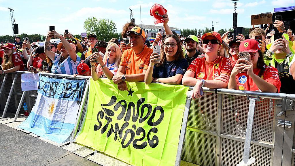 Fans stand in front of banners for Lando Norris and franco Colapinto in the fan zone