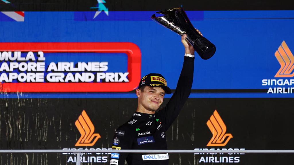 Lando Norris smiles as he raises the trophy for winning the Singapore Grand Prix