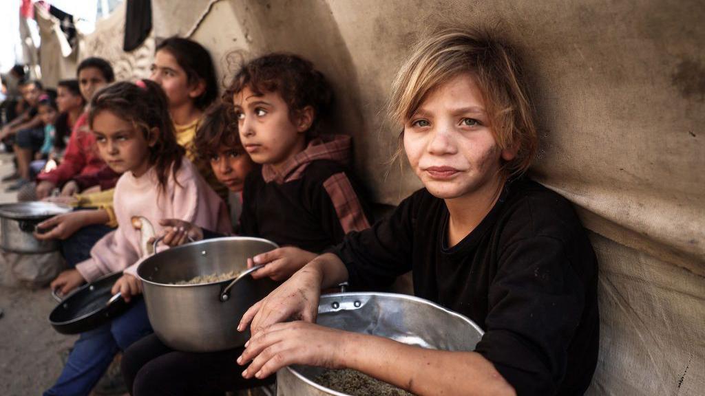 Palestinian children collect aid food at Bureij refugee camp in the central Gaza Strip (6 November 2024)