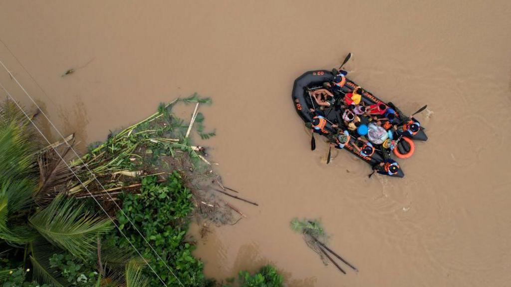 An aerial view shows a coast guard rescue boat evacuating residents to safer gounds in Polangui town, Albay province South of Manila on October 23, 2024.