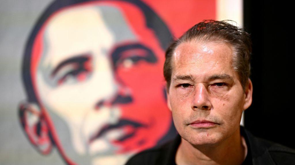 Artist Shepard Fairey in front of his famous work depicting President Barack Obama in red, white and blue shades with the word 'hope' underneath the image