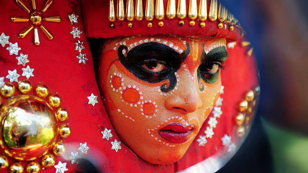 An Indian 'Theyyam' artist with his face painted waits to perform during the 'Kummati Kali' as part of the annual Onam festival celebrations in Thrissur district of southern Kerala state on September 15, 2016. The Theyyam worship rituals are part of several thousand year-old traditions and customs celebrated in Kerala state