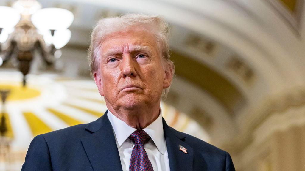 Donald Trump looks serious wearing a blue suit and silk tie