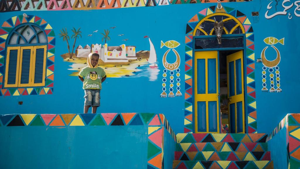 A boy stands in front of a painted house