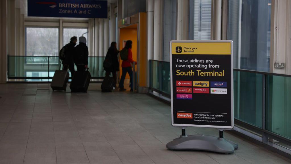 An airport corridor. There is a sign saying South Terminal. 