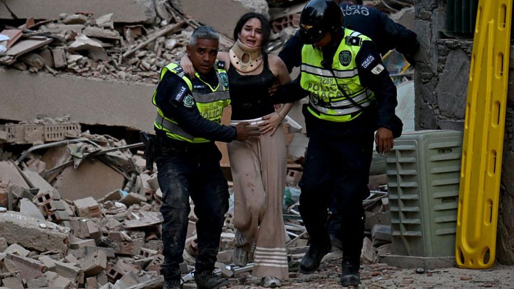 Municipal police officers evacuate an injured victim from a collapsed building