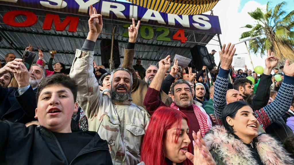 Syrians make the V-sign with their fingers as they gather for a celebratory rally in Sweida, a mainly Druze city in south-western Syria