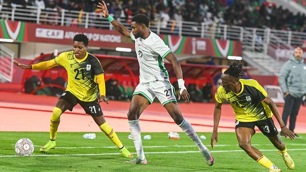 Ryan Alebiosu battles for the ball against two Uganda players