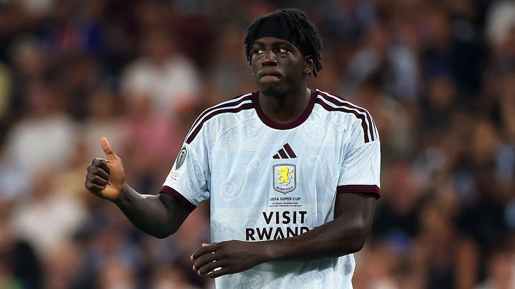 Brian Madjo looks to his right and gives a thumbs up while playing for Aston Villa