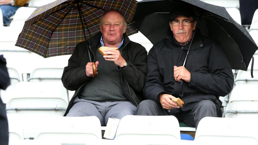 Fans eat snacks in the rain