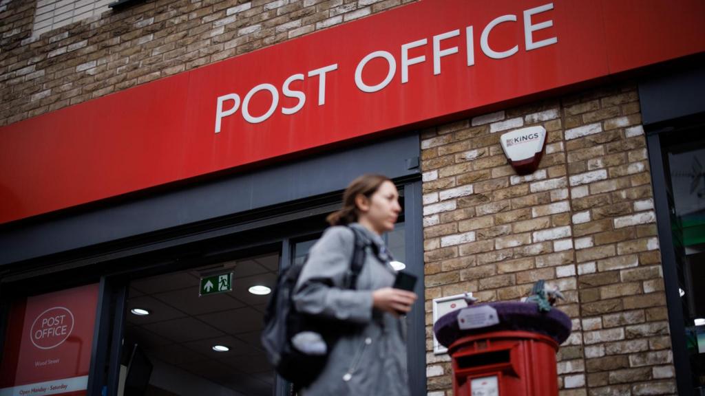 A woman walks past a Post Office branch in east London, Britain.