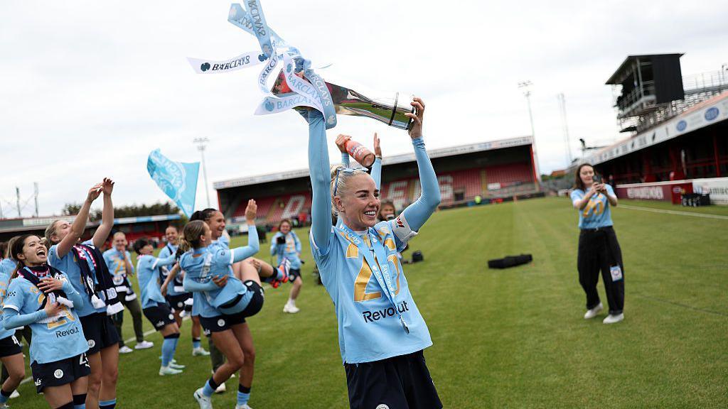 Alex Greenwood lifts the trophy in front of fans