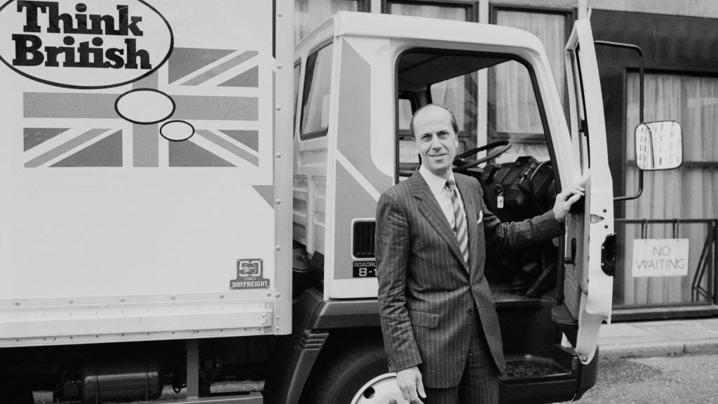 Norman Tebbit in front of a lorry with a Think British slogan