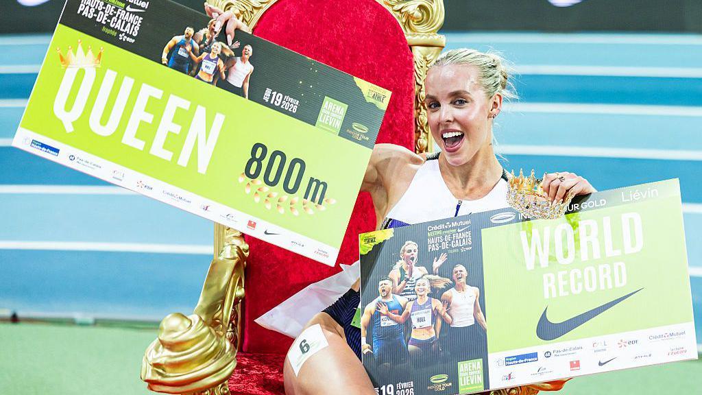 keely sitting on a throne holding signs with her records on