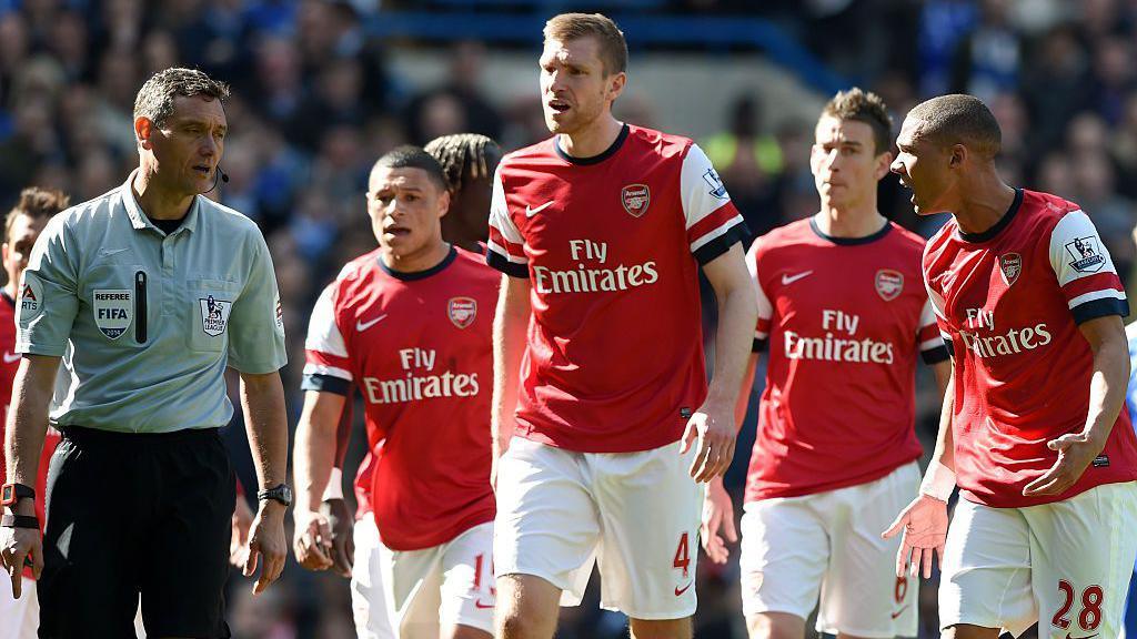 Alex Oxlade-Chamberlain (segundo desde la izquierda) observa mientras el árbitro Andre Marriner (izquierda) le muestra la tarjeta roja a su compañero de equipo Kieran Gibbs (derecha).