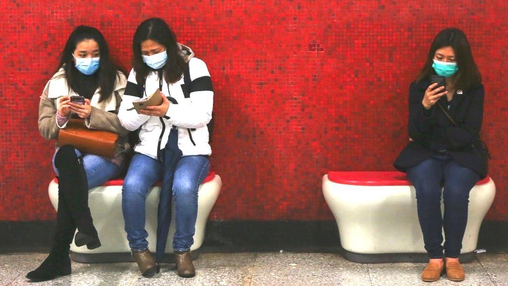 People wearing masks looking at phones