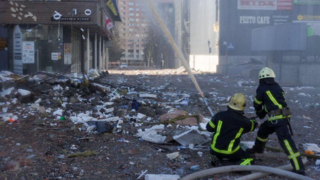 Firefighters work by a residential building hit by a missile strike in the morning in Kyiv on 26 February